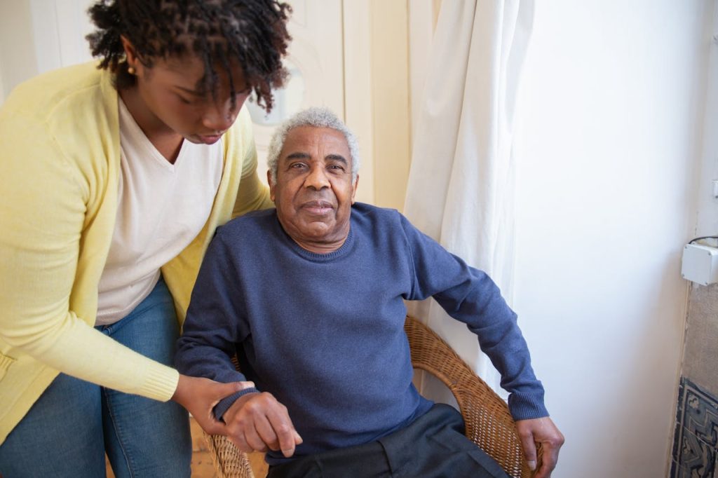 woman-assisting-elderly-man-7551667 A woman assists an elderly man indoors, focusing on care and support.